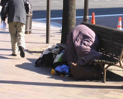 unhoused person laying on a bench