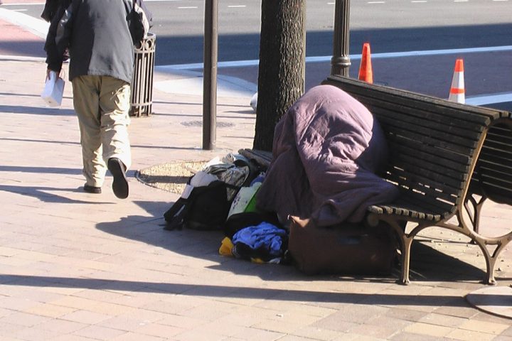 unhoused person laying on a bench
