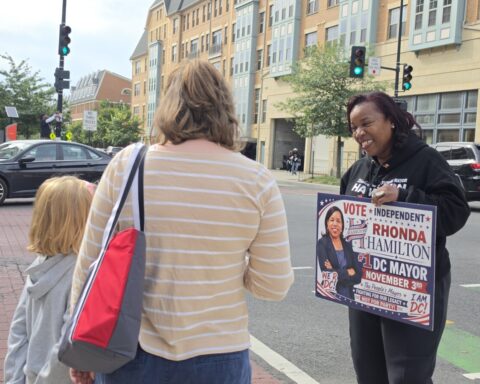 Rhonda Hamilton, the independent candidate for D.C. mayor, talks with a mother and daughter in Ward 5 near Catholic University of America about sports and athletics — the girl enjoys the breaststroke when she swims. (Photo: Myla S. Roundy/HU News Service)