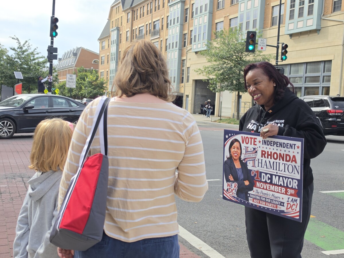 Rhonda Hamilton, the independent candidate for D.C. mayor, talks with a mother and daughter in Ward 5 near Catholic University of America about sports and athletics — the girl enjoys the breaststroke when she swims. (Photo: Myla S. Roundy/HU News Service)